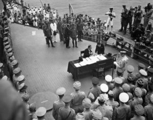 Original caption: Tokyo, Japan: Ceremonies of the Japanese surrender on board the battleship Missouri, 1945. Japanese Foreign Minister Shigemitsu signs as MacArthur braodcasts ceremonies. September 2, 1945 Tokyo, Japan